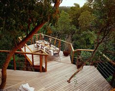 an outdoor deck with chairs and tables surrounded by trees