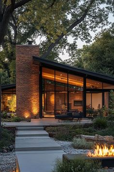 a fire pit sitting in the middle of a garden next to a building with glass walls