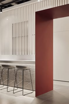 two bar stools in front of a wall with vertical slats on the walls