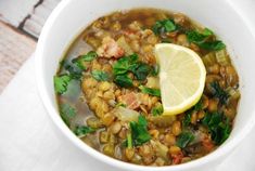 a white bowl filled with soup and a lemon wedge