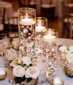 candles and flowers are sitting on a table with other items in the centerpieces