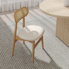 a white chair sitting in front of a table with a vase on it's side