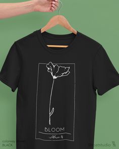 a black t - shirt with a white flower on it and the word bloom printed on it