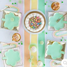 a table topped with plates and desserts covered in frosted food next to candy