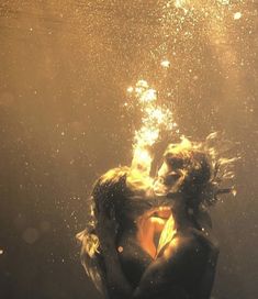 two people are kissing under water in the ocean, with bubbles coming from their backs