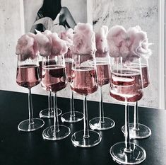 five wine glasses with pink flowers in them on a black table next to a framed photo