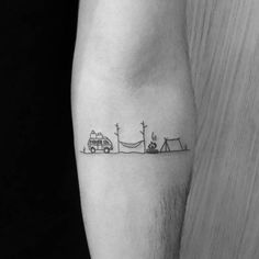 a black and white photo of a person's arm with a small camper on it