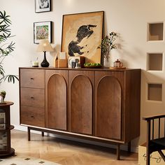 a wooden cabinet sitting in the middle of a living room with pictures on the wall