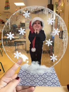 a person holding up a snow globe with an image of a child in the center