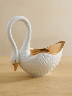 a white swan shaped bowl sitting on top of a wooden table