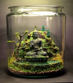 a glass jar filled with green moss and a buddha statue in the bottom right corner