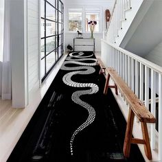 a black and white hallway with an artistic design on the floor, along with a bench