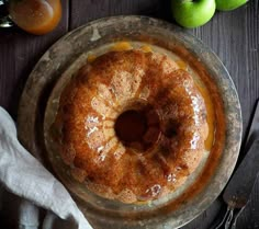 a bundt cake sitting on top of a plate next to some apples and silverware