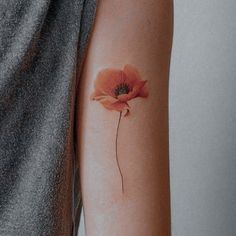 a woman's arm with an orange flower tattoo on the left side of her arm