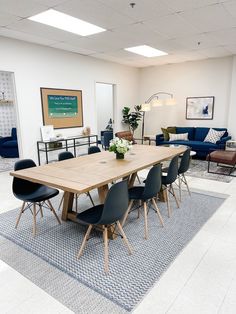 a large wooden table surrounded by chairs and couches in a room with white walls