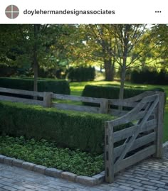 a wooden fence surrounded by hedges in a park