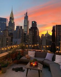 a couch and table on a roof with city lights in the background