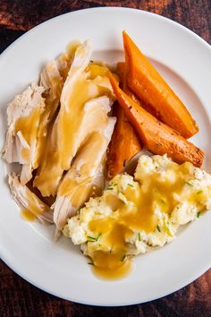 a plate with mashed potatoes, carrots and chicken on it next to gravy