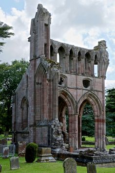 an old church with stone arches and graves in the foreground, on a cloudy day