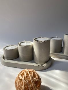 three candles are sitting on a tray next to a ball of yarn