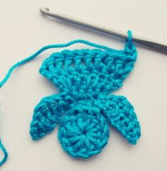 a crochet flower is being worked on by a knitting needle and yarn ball