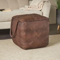 a brown leather ottoman sitting on top of a rug