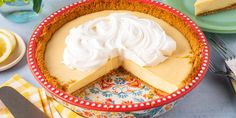 there is a pie with whipped cream on top in a bowl next to plates and utensils