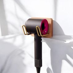 a hair dryer on a white wall with a wooden holder attached to the wall