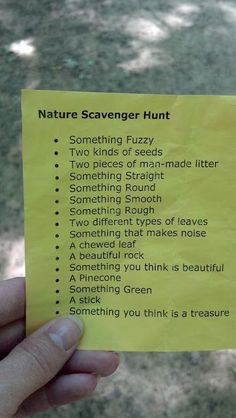 a hand holding a yellow post it note with words on it that say nature scavenger hunt