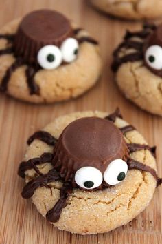 cookies decorated with googly eyes and spider webs are on a wooden table, ready to be eaten