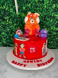 a birthday cake with an orange teddy bear and other toys on it's top