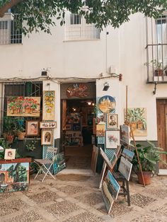 there are many paintings on display in front of the building that has it's doors open