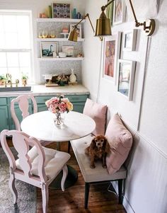 a dog sitting on a chair at a table in a room with white walls and wooden floors