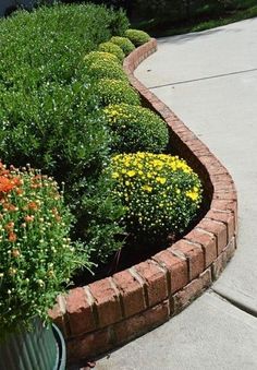 a planter filled with lots of flowers next to a sidewalk