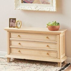 a wooden dresser with a potted plant on top next to a framed photo and clock