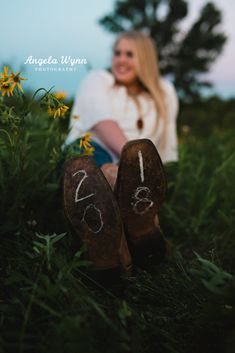 a woman is sitting in the grass with her feet up and numbers painted on them