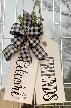 two wooden signs hanging from the side of a building with a bow on it's front door