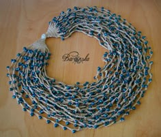 a blue and white beaded necklace with tassels on it's sides