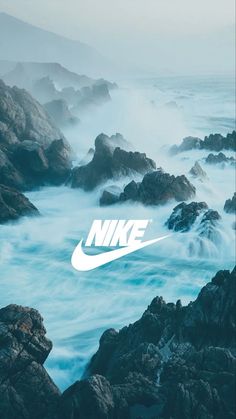 the nike logo is on top of rocks in the ocean with waves crashing around it