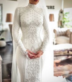 a woman in a white wedding dress standing next to a couch