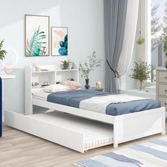 a white bed sitting next to a blue dresser in a room with wooden flooring