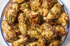 a white plate topped with chicken wings covered in parsley