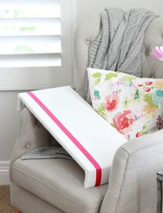 a chair with pillows and a pillow on top of it next to a flower in a vase