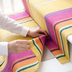 a woman is making a colorful blanket on a couch