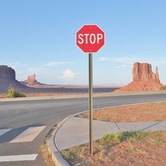 a red stop sign sitting on the side of a road next to a desert landscape