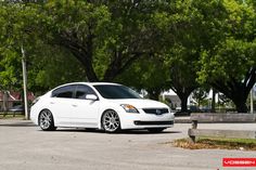 a white car parked in front of some trees