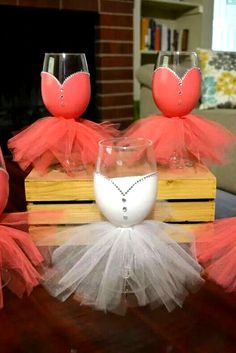 some wine glasses are sitting on top of a wooden box with tulle skirts around them