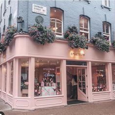 a pink store front with flowers on the windows