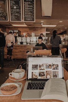 an open laptop computer sitting on top of a wooden table next to a cup of coffee