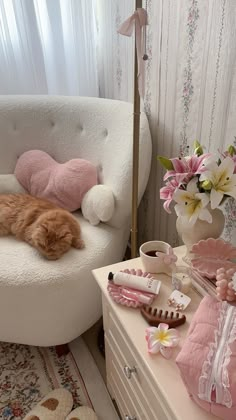 an orange cat laying on top of a white chair next to a table with flowers